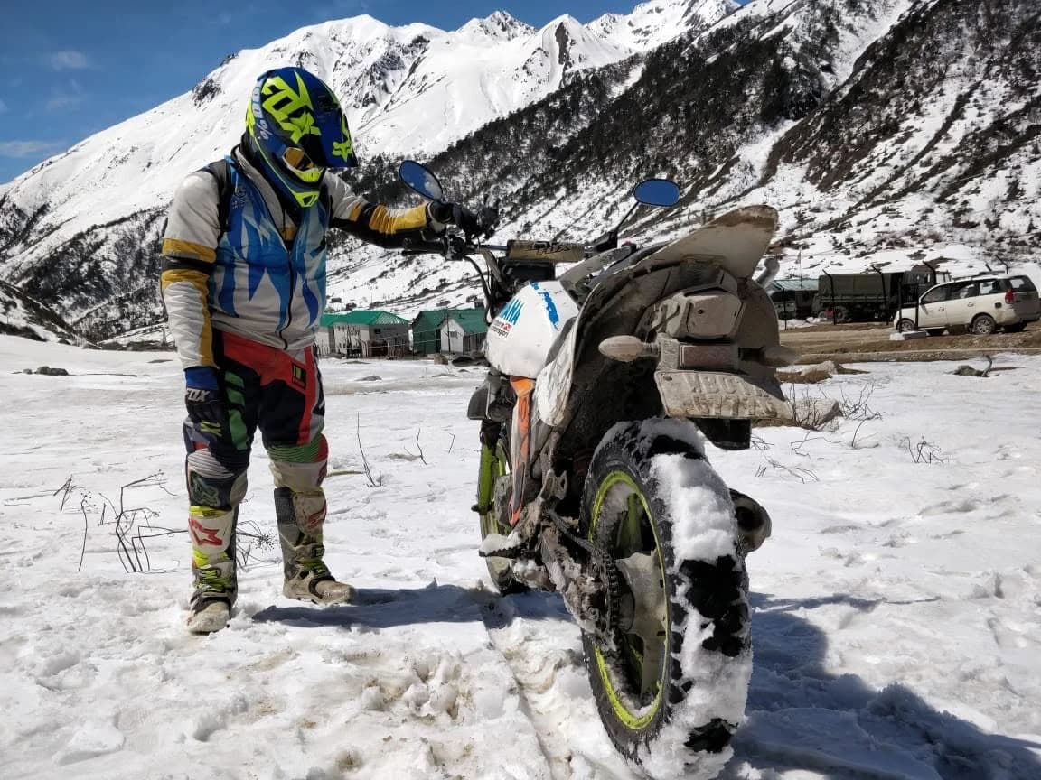 Motology rider checking a motorcycle in deep Himalayan snow