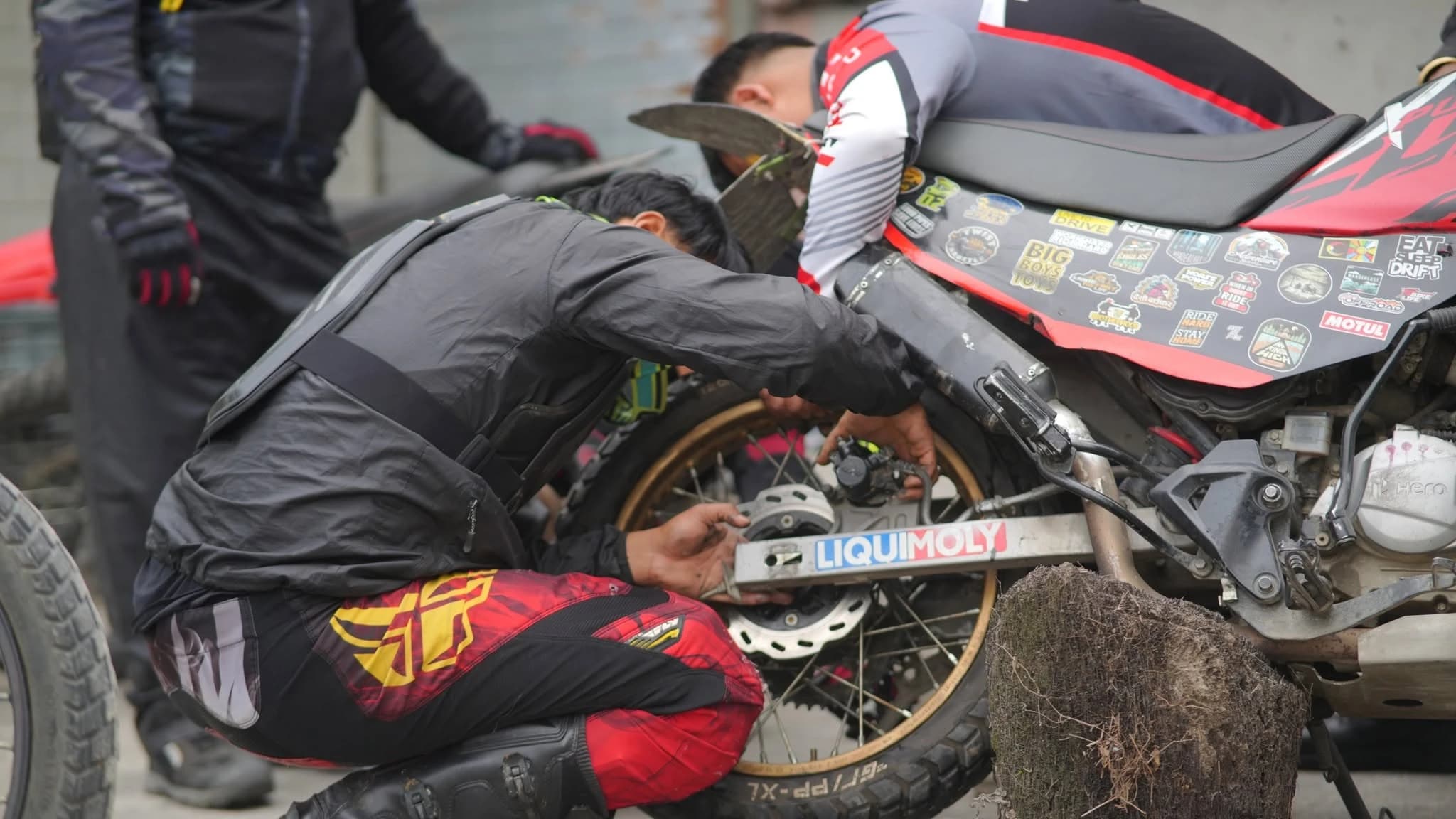 Motology riders repairing an adventure motorcycle beside the road